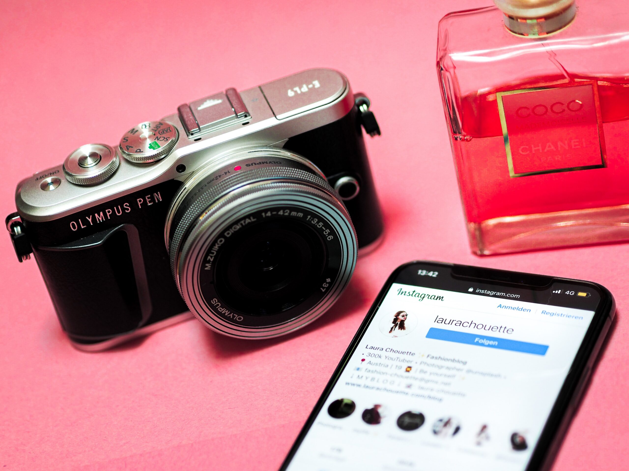 A camera and phone and perfume bottle on a table
